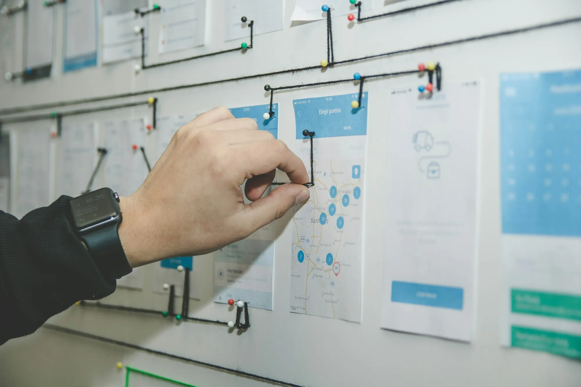 Interface wireframes pinned to a wall during a design review