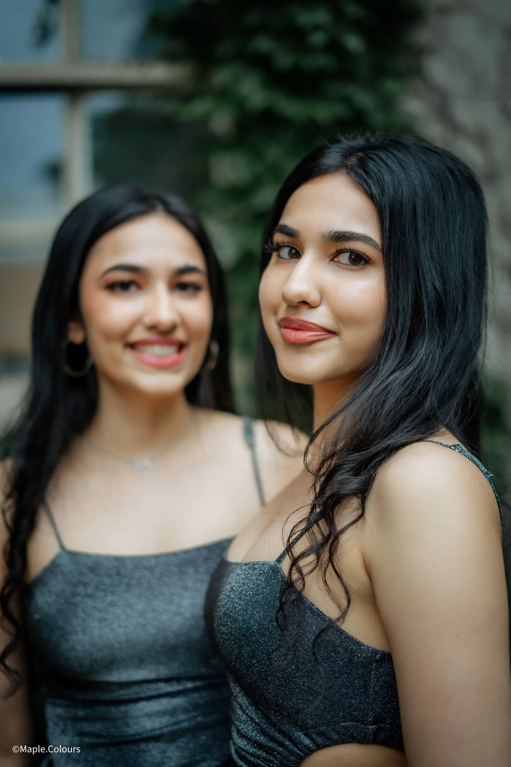 Two friends photographed together against a garden wall