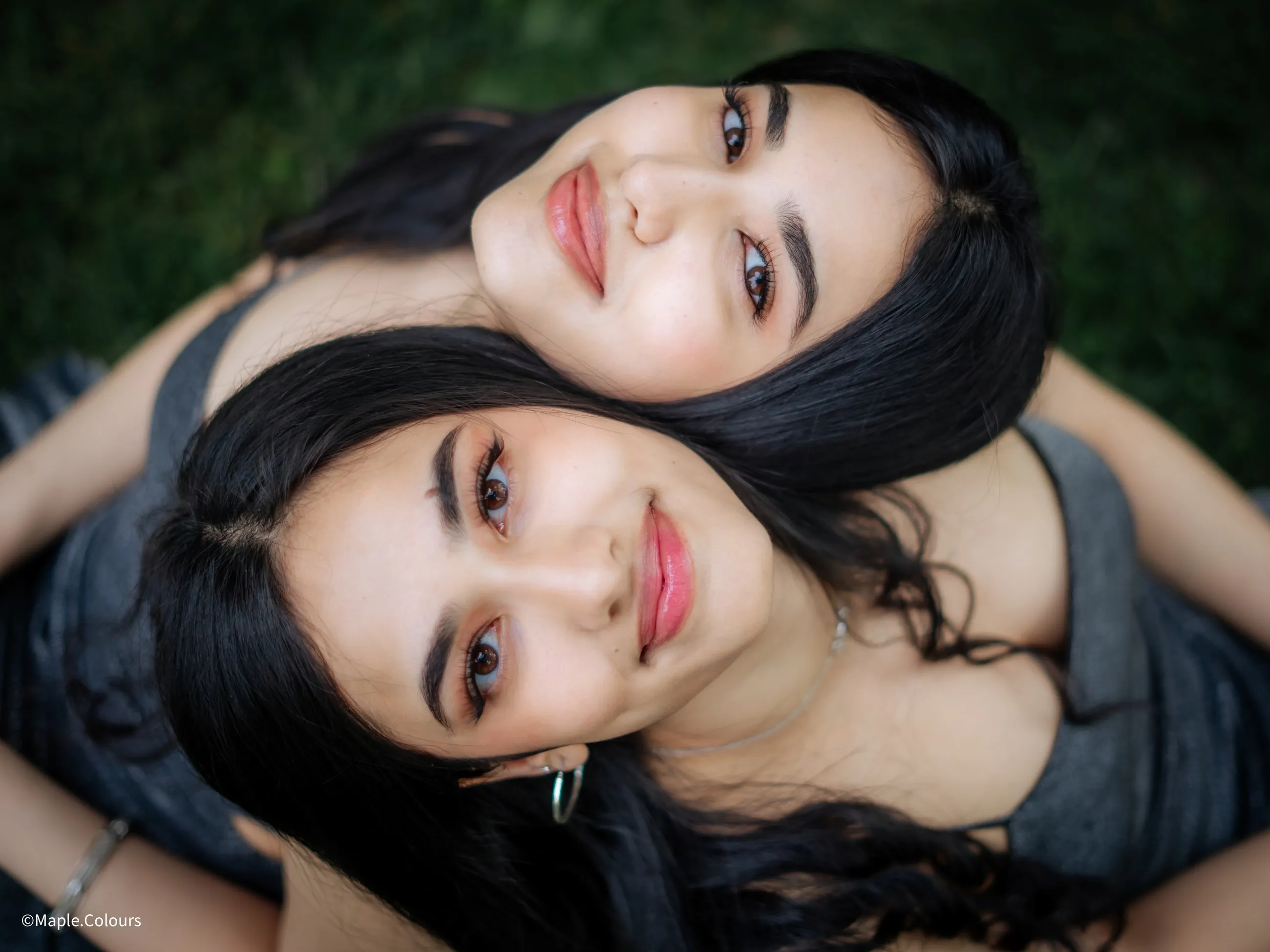 Overhead portrait of two friends lying on summer grass
